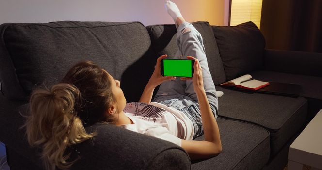 Woman staying home and waching horizontal phone Green Mock-up Screen Chroma key.