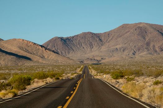 Wavy road and some mountains in the background in Death Valley in the USA
