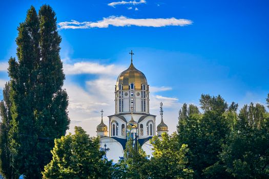 a building used for public Christian worship.Golden church, blue sky and green trees in sunny day. High quality photo