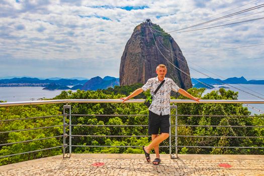 Tourist traveler is posing at the Sugarloaf sugar loaf mountain Pão de Açucar with cable car panorama view in the Urca village in Rio de Janeiro Brazil.