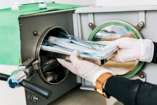 A dentist sterilizing his tools, Dentist with a dental sterilizer,  A dentist with a dental autoclave, Close up of a dentist with a steam sterilizer