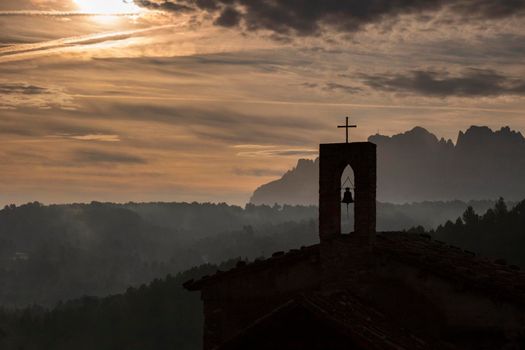 Misty morning in Montserrat and a small church silhouette from Sant Salvador de Guardiola
