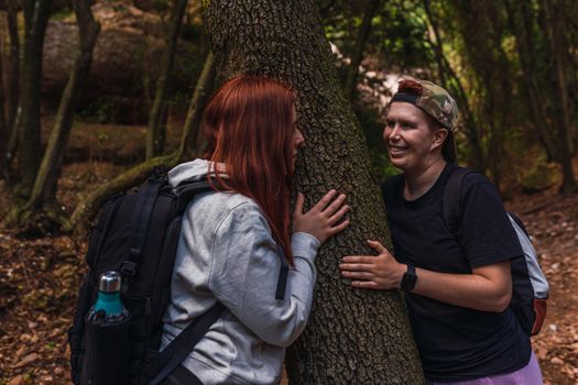 young women relaxing and enjoying themselves on a mountain trail. tourists hiking in nature. young people on holiday. hiking poles and mountaineer's backpack. natural and warm light. lush vegetation. hiking poles.