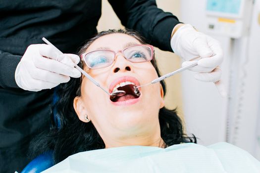 Female dentist checking a patient, close up of dentist with patient, dentist performing root canal on patient, dentist performing dental checkup