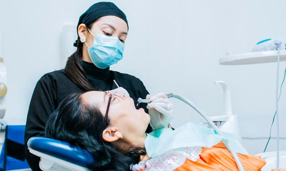 A dentist cleaning a patient's mouth, a dentist cleaning a patient's caries, a dentist cleaning a patient's mouth, The stomatologist cleaning a patient's teeth