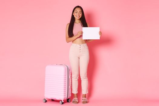 Travelling, holidays and vacation concept. Full-length of asian cute exchange student arrive at country with suitcase, holding piece of paper and smiling, searching for host-family in airport.
