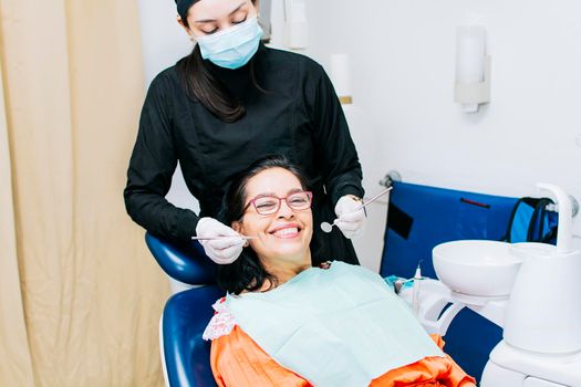 Dentist examining mouth to smiling patient, Female dentist doing root canal to female patient, Female dentist with lying patient, Dentist performing stomatology