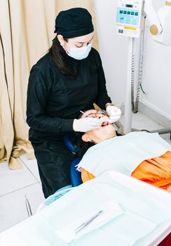 Dentist with patient lying down, Dentist examining mouth to patient, Woman dentist doing endodontics to woman patient, Dentist performing stomatology