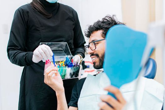 Patient with dentist choosing dental braces, Dentist with patient choosing metal braces, Patient with dentist choosing rubber band