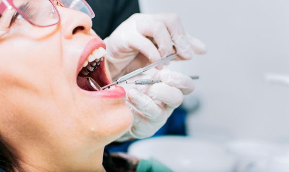 Close up of patient checked by dentist, Dentist checking patient's mouth, close up of dentist's hands checking patient's mouth, Dentist performing stomatology