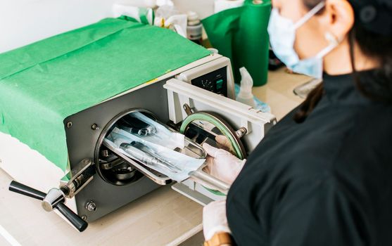A dentist sterilizing his tools, Dentist with a dental sterilizer,  A dentist with a dental autoclave, Close up of a dentist with a steam sterilizer