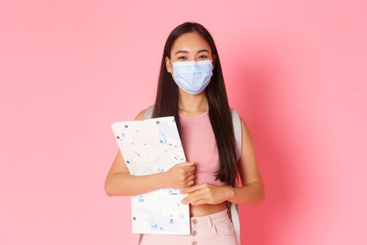Safe tourism, travelling during coronavirus pandemic and preventing virus concept. Cute asian girl travel abroad, tourist in medical mask with map going sightseeing, social distancing during journey.