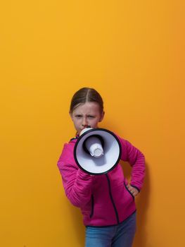 Funny little kid girl Screaming in megaphone over the yellow background in studio. People sincere emotions lifestyle concept. Mock up copy space. High quality photo