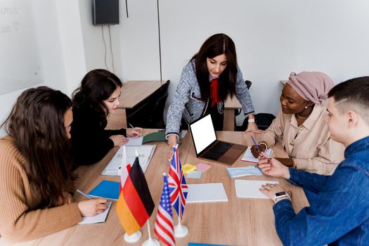 Teamwork. Working in multiethnic group of students. teacher study foreign languages together in class. Studing with laptop. Black handsome girl student study with white people together