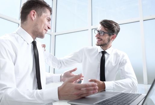 Two businessmen are sitting in the office and discussing the conclusion of a new deal