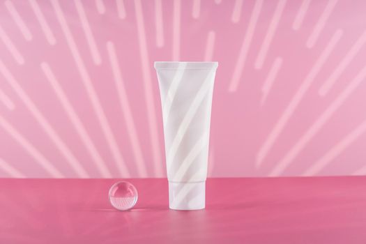 Unbranded cosmetic cream white plastic tube mockup on pink background with stylish props. Blank body and health care beauty product packaging. Moisturising hand creme bottle. Product presentation