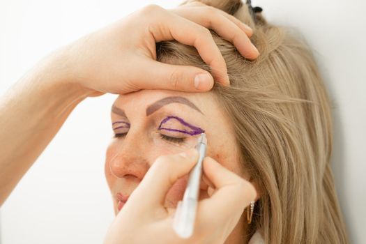 Blepharoplasty markup close-up on the face before the plastic surgery operation for modifying the eye region of the face in medical clinic. Doctor doing plastic cosmetic operation