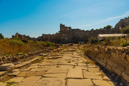 SIDE, TURKEY: Ancient ruins and a road in the city of Side on a sunny summer day against the background of a blue sky. Side, Antalya province, Turkey.