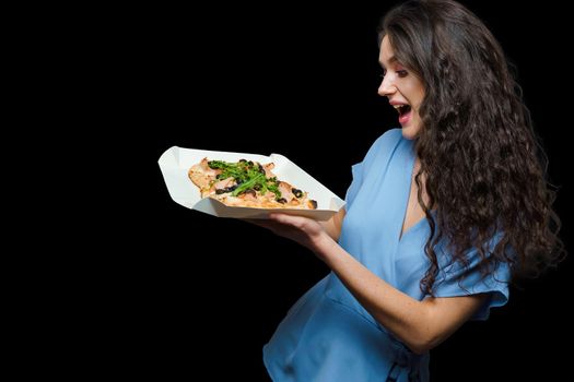 Woman courier with pinsa romana gourmet italian cuisine on black background. Holding scrocchiarella traditional dish. Food delivery from pizzeria. Pinsa with meat, arugula, olives, cheese