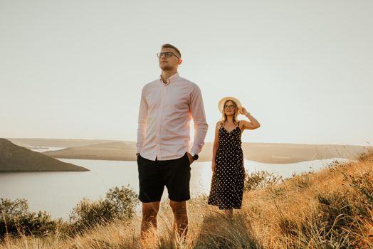 woman behind man in rays of setting sun in summer near lake