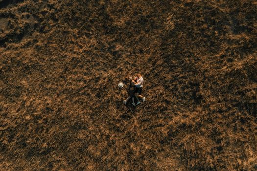couple of people in love lies in high grass in meadow at sunset top view from drone