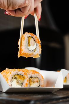 Sushi roll on the food delivery plate. Roll with salmon, mango and soft cheese