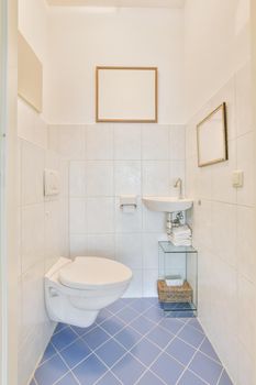 Bathroom interior with white and blue tiles and ceramic sink and hinged toilet in a modern apartment