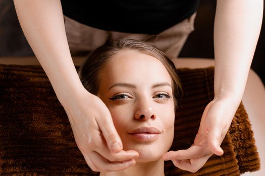 Masseur is making facial massage in spa for model with perfect skin. Beauty procedure