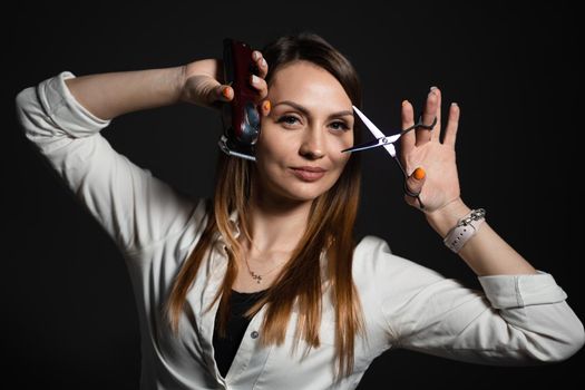 Woman barber with scissors and hair clipper in barbershop. Portrait of hairdresser for advert