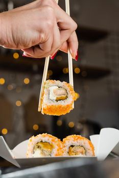 Sushi and roll food delivery at new year eve. Christmas celebration with roll with salmon, mango and soft cheese