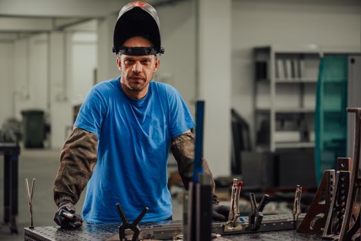 Portrait of Young Professional Heavy Industry Engineer. Worker Wearing Safety Vest and Hardhat Smiling on Camera. In the Background Unfocused Large Industrial Factory . High quality photo