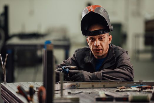 Professional Heavy Industry Welder Working Inside the factory, Wears Helmet and Starts Welding. Selective Focus. High-quality photo