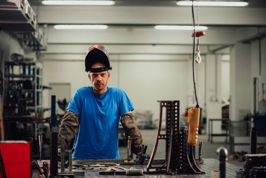 Portrait of Young Professional Heavy Industry Engineer. Worker Wearing Safety Vest and Hardhat Smiling on Camera. In the Background Unfocused Large Industrial Factory . High quality photo