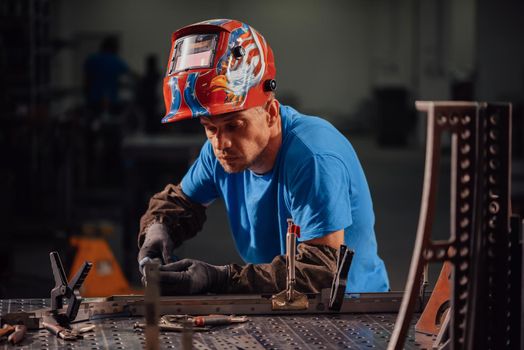 Professional Heavy Industry Welder Working Inside the factory, Wears Helmet and Starts Welding. Selective Focus. High-quality photo