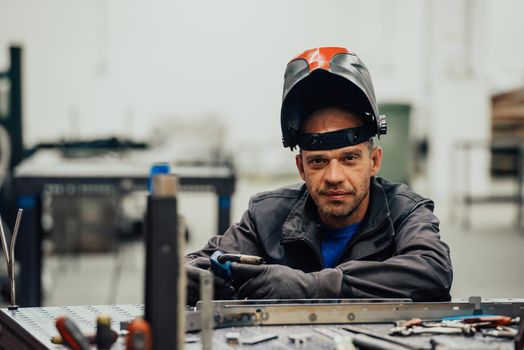 Professional Heavy Industry Welder Working Inside the factory, Wears Helmet and Starts Welding. Selective Focus. High-quality photo