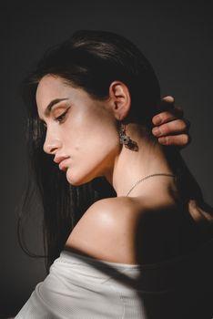 portrait of beautiful gentle woman in a white bodysuit posing in the sunshine. Black long hair. sensuality and tenderness.