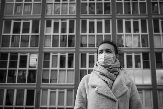 Shot of a girl in wearing face mask for protection, on the street. Against the background of a residential building with windows. lockdown Covid-19 pandemic.