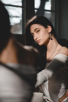 portrait of beautiful gentle woman in a white bodysuit posing in the sunshine. Black long hair. sensuality and tenderness.