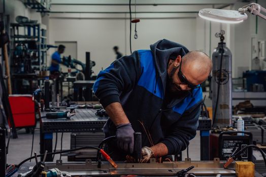 Industrial worker man soldering cables of manufacturing equipment in a factory. Selective focus. High-quality photo