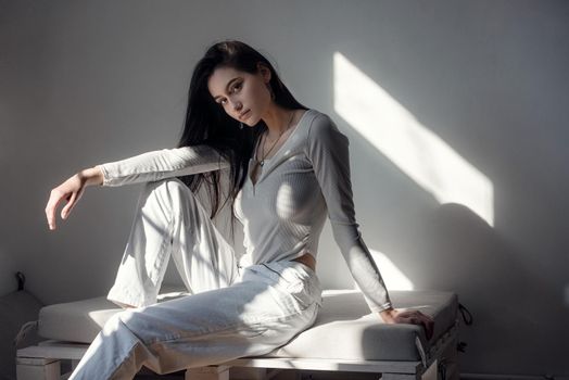 portrait of beautiful gentle woman in a white bodysuit posing in the sunshine. Black long hair. sensuality and tenderness.