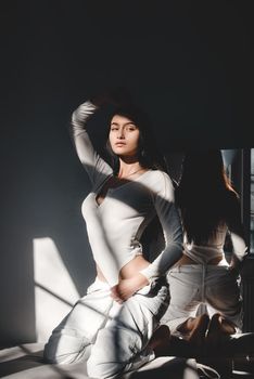 portrait of beautiful gentle woman in a white bodysuit posing in the sunshine. Black long hair. sensuality and tenderness.