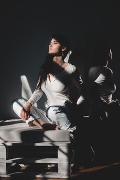 portrait of beautiful gentle woman in a white bodysuit posing in the sunshine. Black long hair. sensuality and tenderness.