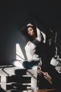 portrait of beautiful gentle woman in a white bodysuit posing in the sunshine. Black long hair. sensuality and tenderness.