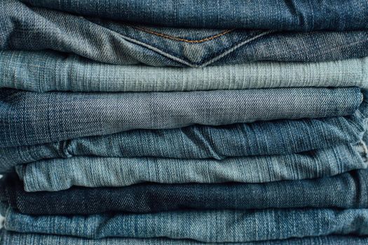 Stack of a stack of old jeans various shades of blue jeans. Denim jeans texture. Denim background texture for design. Canvas denim texture. Blue denim background.