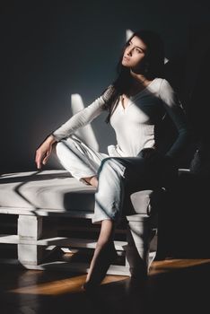 portrait of beautiful gentle woman in a white bodysuit posing in the sunshine. Black long hair. sensuality and tenderness.