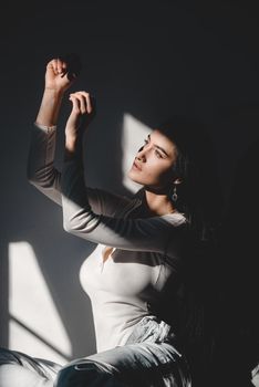 portrait of beautiful gentle woman in a white bodysuit posing in the sunshine. Black long hair. sensuality and tenderness.