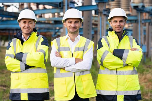 Group portrait of multiethnic industrial workers team consist of technicians, engineers, mechanic wearing helmet uniform looking camera. Industrial workers, electric industry, production concept.