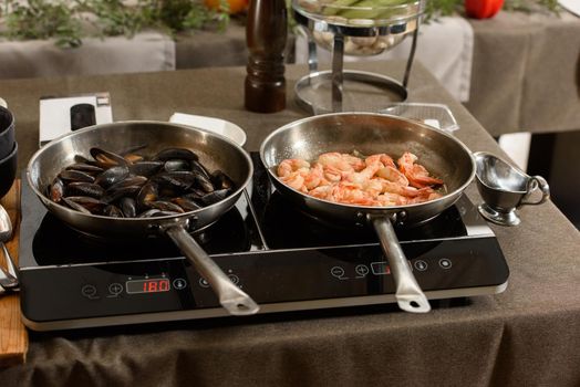 Fried red shrimps with garlic in olive oil in a metal pan on stove. Step by step cooking of sea food pasta.