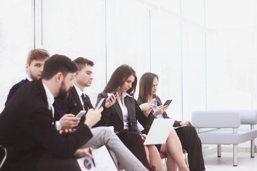 business team uses laptops and smartphones while sitting in the office lobby.Internet lifestyle generation.