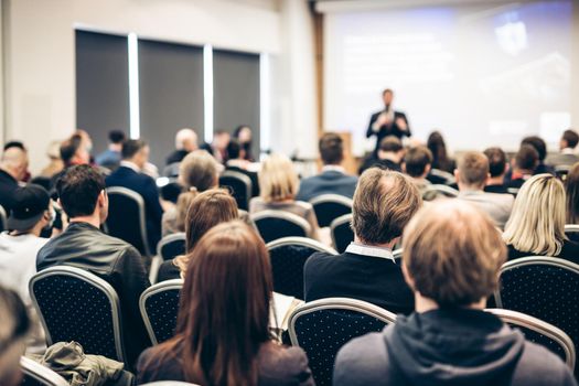 Speaker giving a talk in conference hall at business event. Rear view of unrecognizable people in audience at the conference hall. Business and entrepreneurship concept